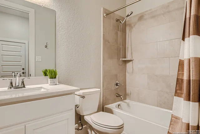 a bathroom with a granite countertop bathtub shower sink vanity mirror and toilet