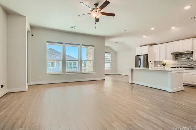 a view of an empty room with a window and wooden floor