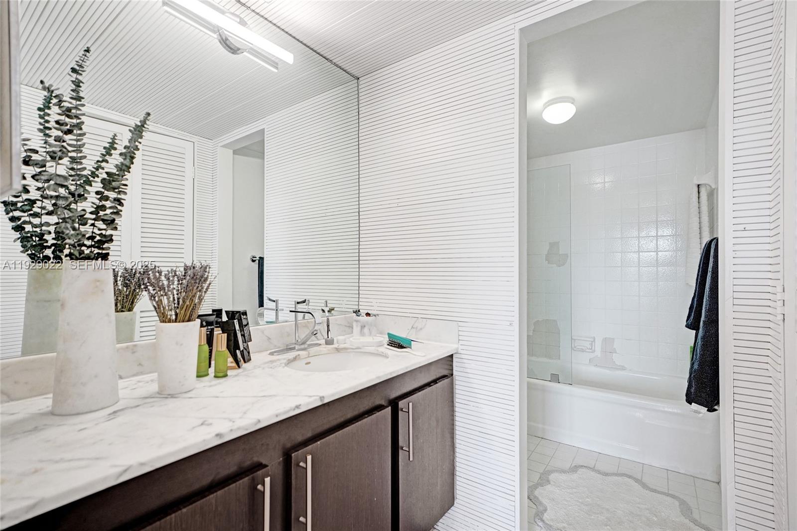600 Northeast 36th Street, Unit 218 Miami, FL 33137 - Photo 6 of 31 a bathroom with a granite countertop sink and a mirror