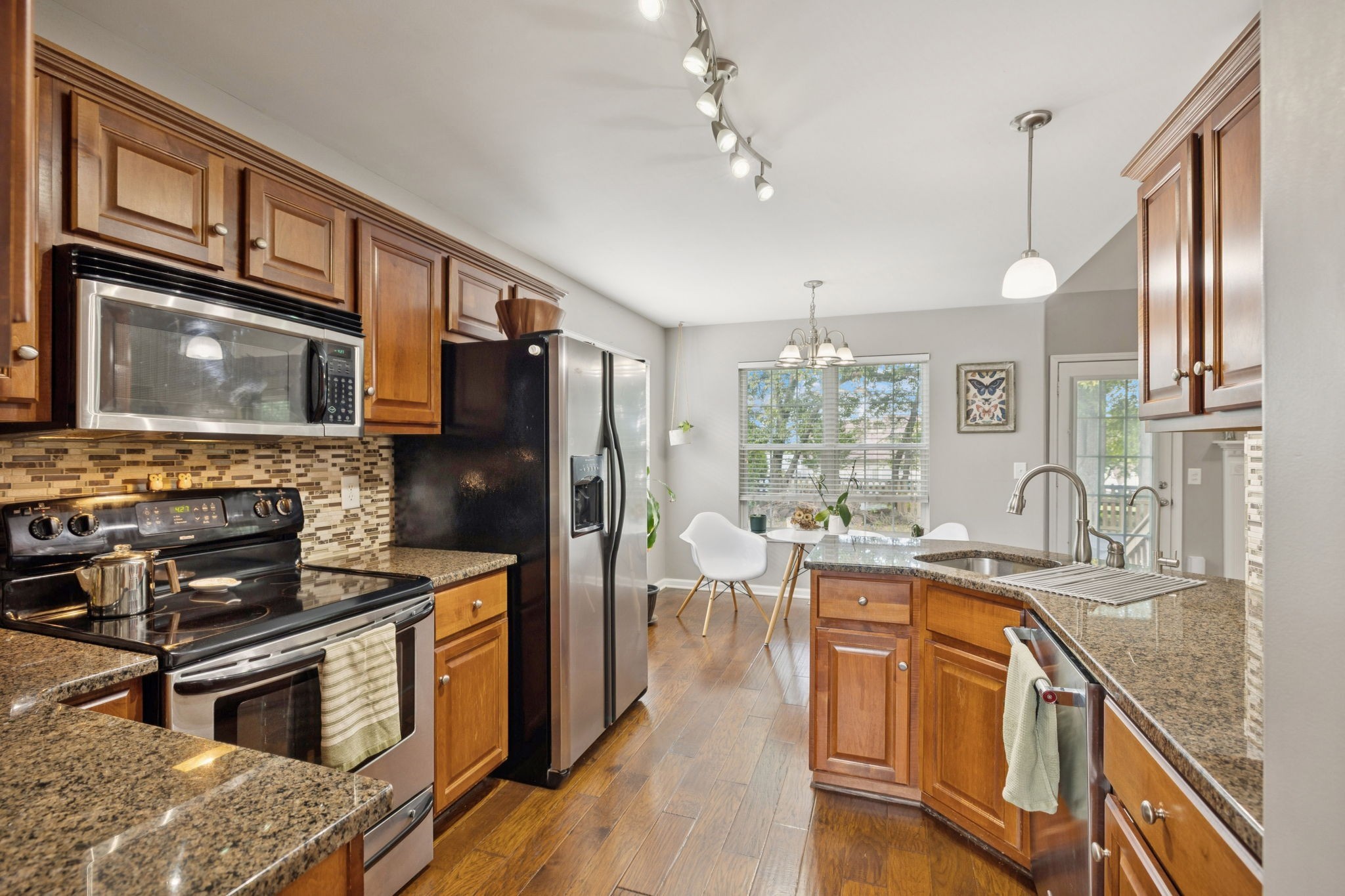 1062 Golf View Way Spring Hill, TN 37174 - Photo 16 of 42 a kitchen with stainless steel appliances granite countertop a stove top oven a refrigerator a sink dishwasher a dining table and chairs with wooden floor