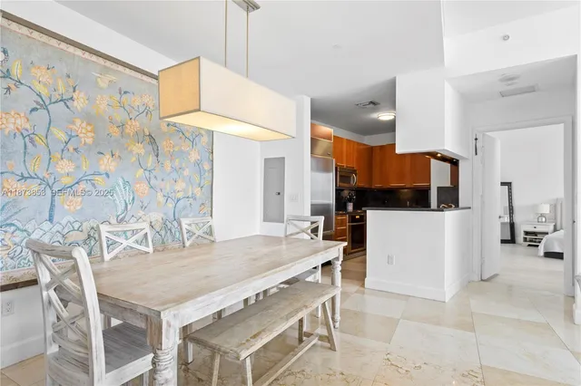 a kitchen with stainless steel appliances kitchen island granite countertop a table chairs and a refrigerator