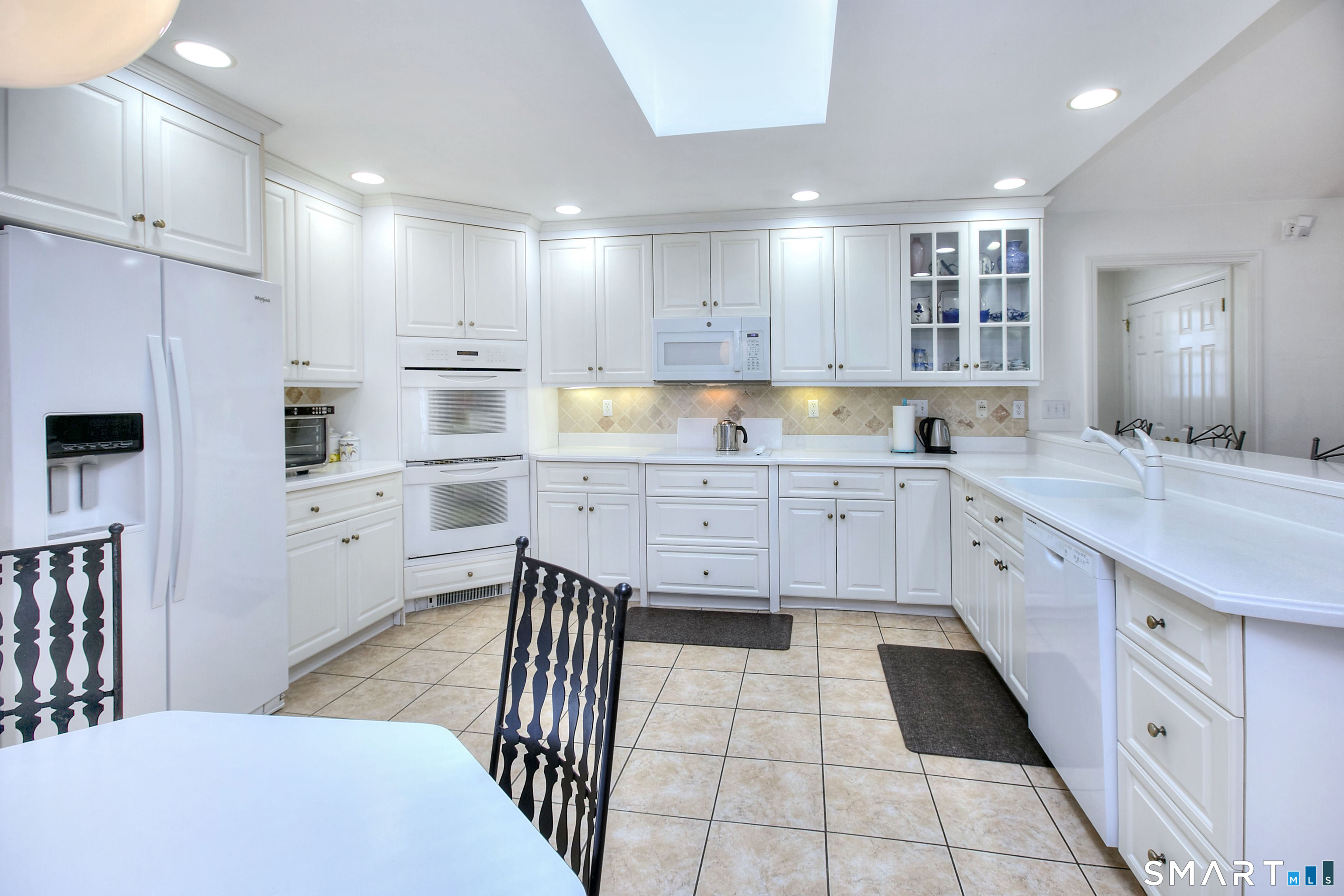 84 Youngstown Road Fairfield, CT 06824 - Photo 4 of 36 a large white kitchen with cabinets a sink a window and stainless steel appliances
