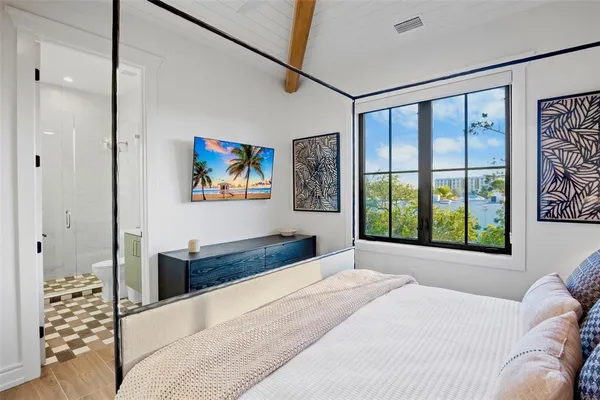 a bedroom with a bed and a flat tv screen on dresser