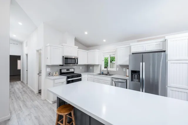 a kitchen with a refrigerator a stove top oven a sink and cabinets