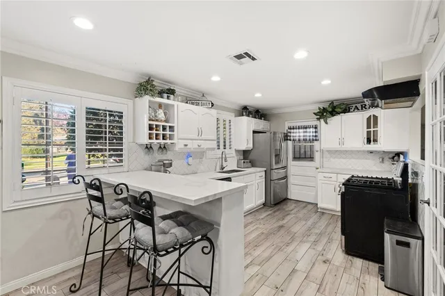 a kitchen with stainless steel appliances kitchen island granite countertop a stove a refrigerator a sink a dining table and chairs with wooden floor