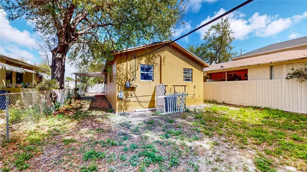 a view of backyard of house with wooden fence and trees
