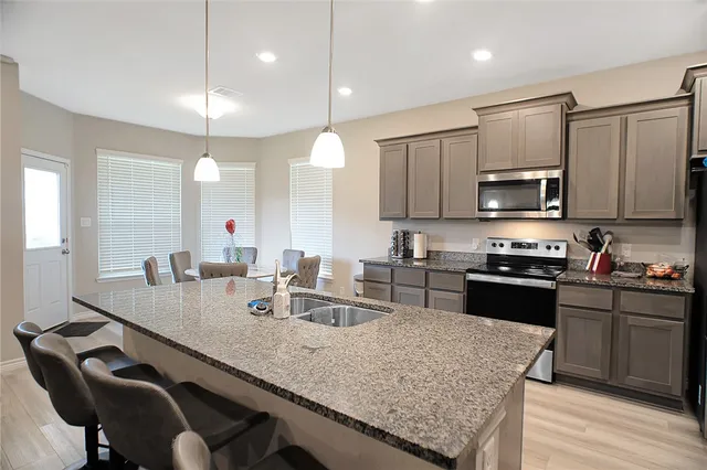 a kitchen with granite countertop a sink chairs and wooden cabinets