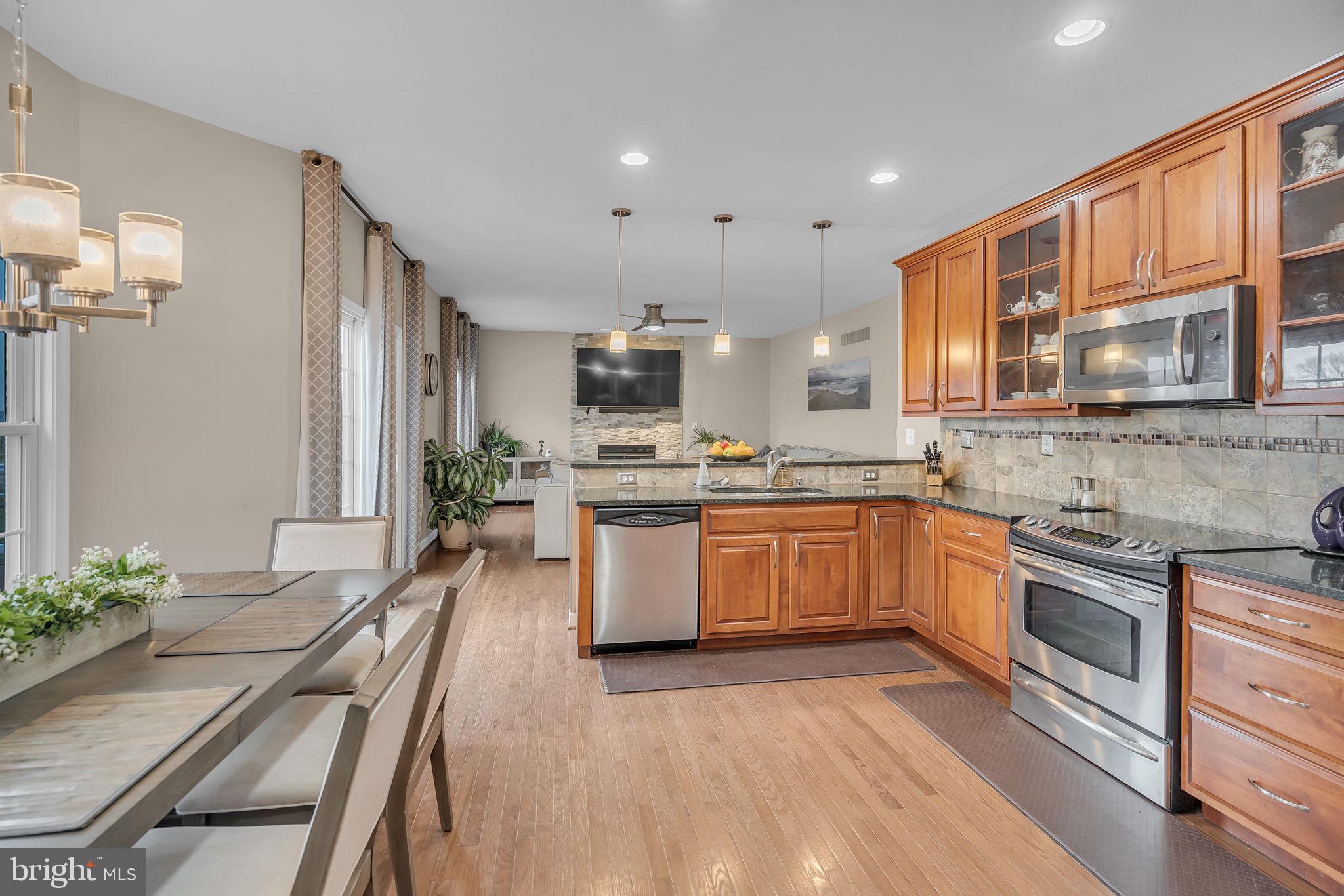 18631 Brick Store Road Hampstead, MD 21074 - Photo 15 of 64 a large kitchen with stainless steel appliances granite countertop a stove top oven a sink dishwasher and white cabinets with wooden floor