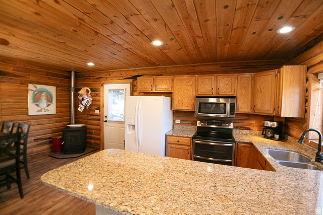 348 North Jakes Pl Road Loa, UT 84747 - Photo 20 of 26 Kitchen with rustic walls, light stone countertops, stainless steel appliances, recessed lighting, and a wood stove