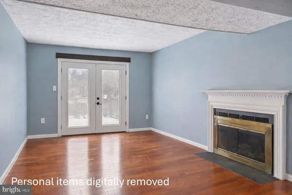 a view of an empty room with wooden floor and a fireplace