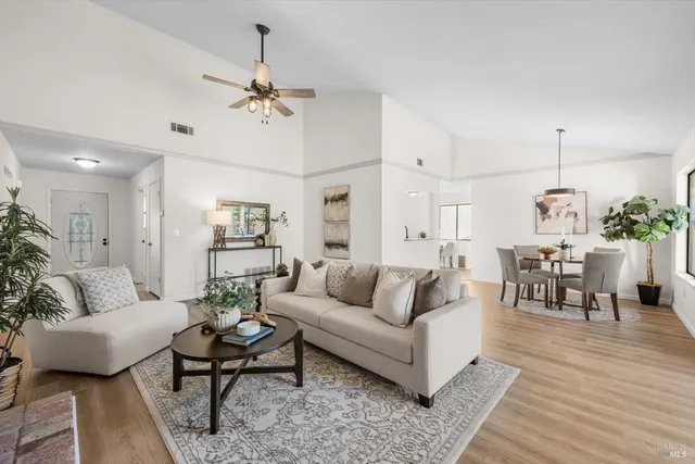 a living room with furniture kitchen view and a chandelier