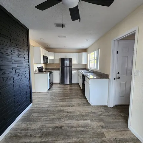 a view of a kitchen with wooden floor and electronic appliances