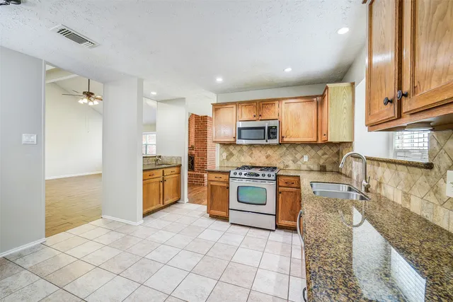 a large kitchen with granite countertop a stove top oven a sink a counter space and cabinets