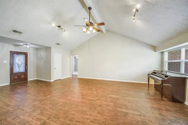 an empty room with windows and ceiling fan