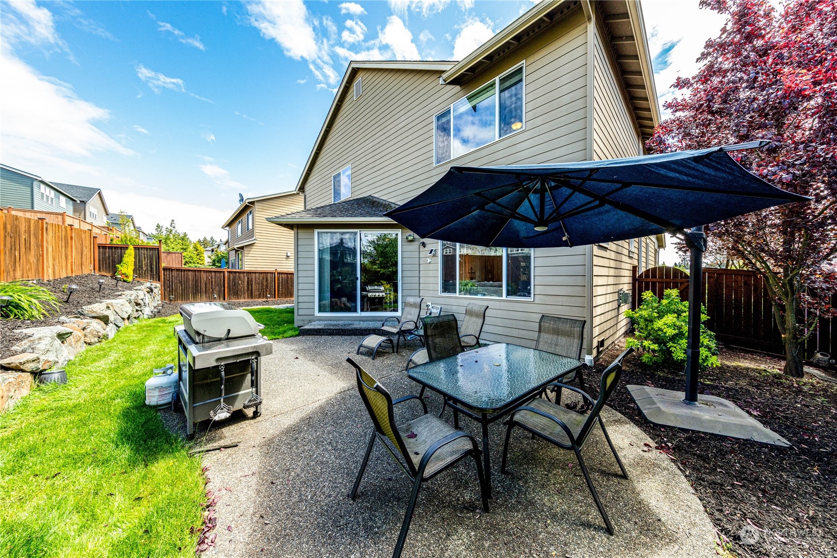 4315 229th Place Southeast Bothell, WA 98021 - Photo 37 of 40 a view of a patio with table and chairs under an umbrella with a barbeque