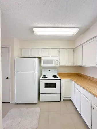 a kitchen with white cabinets and white appliances