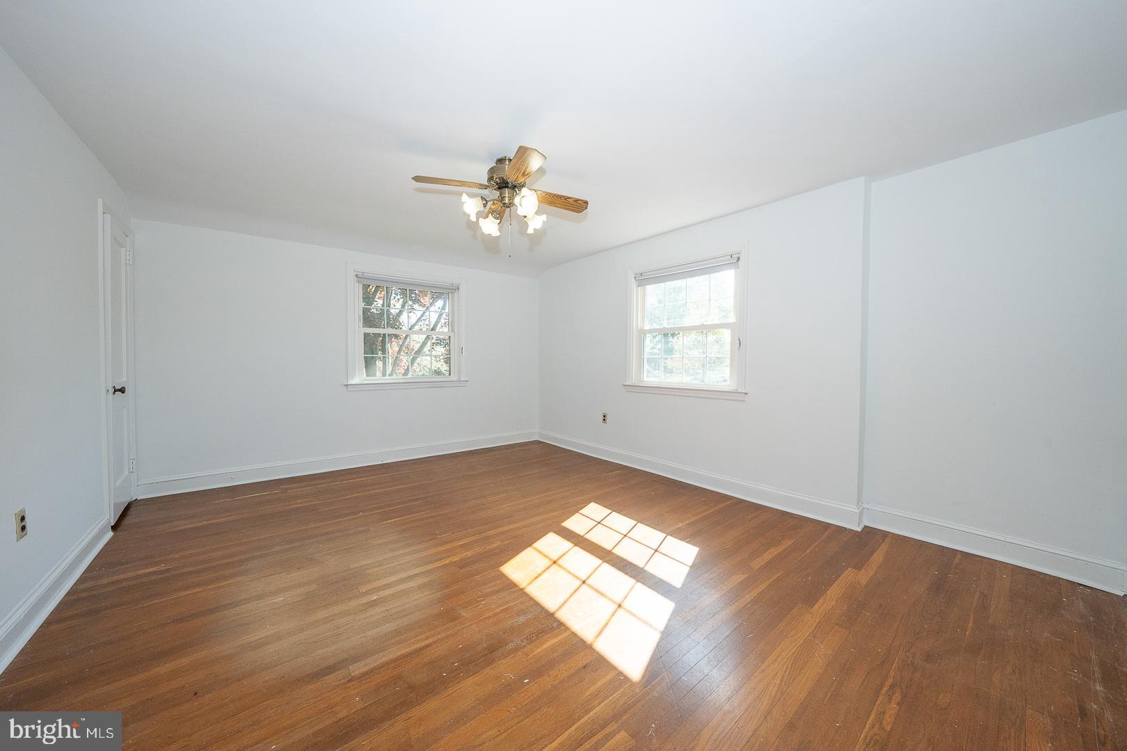 306 Sedgewood Road Springfield, PA 19064 - Photo 26 of 55 an empty room with wooden floor chandelier fan and windows
