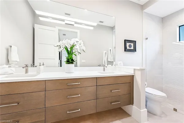 a bathroom with a double vanity sink toilet and a mirror