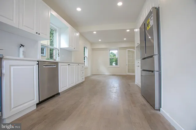 a kitchen with stainless steel appliances granite countertop a refrigerator sink and white cabinets