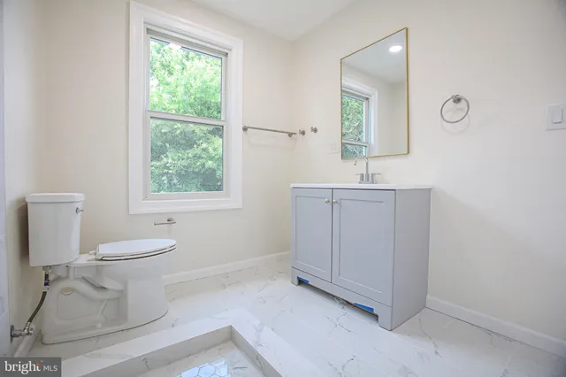 a bathroom with a toilet a sink a window and mirror