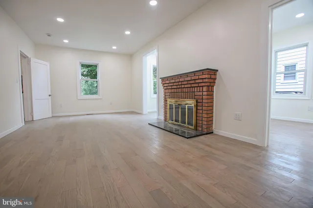 an empty room with wooden floor fireplace and windows