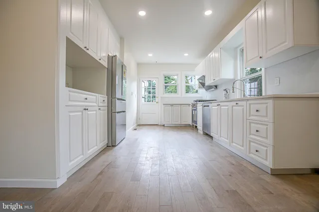 a kitchen with white cabinets and wooden floor