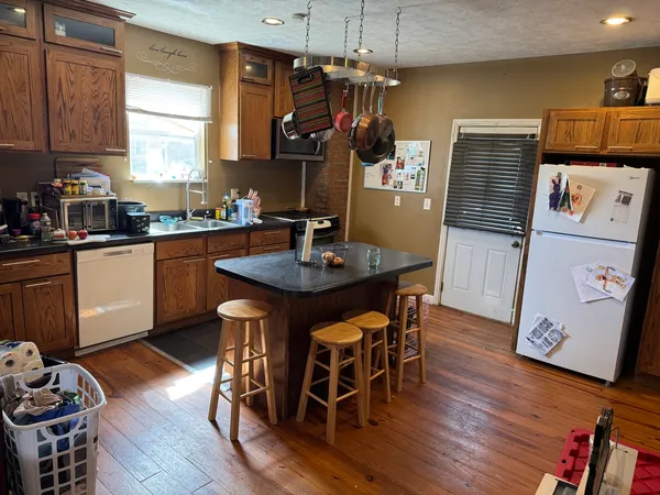 a kitchen with stainless steel appliances granite countertop a kitchen island hardwood floor sink stove dining table and chairs