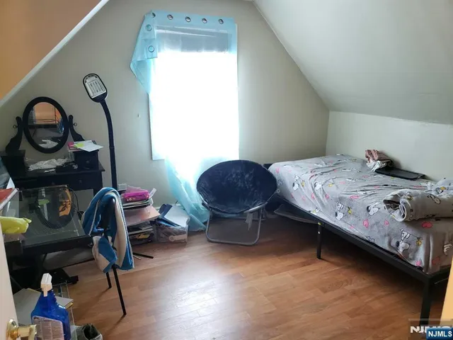 a bedroom with a bed a dresser and next to a window