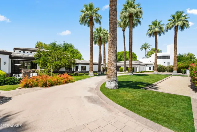 a view of a house with a yard and palm trees