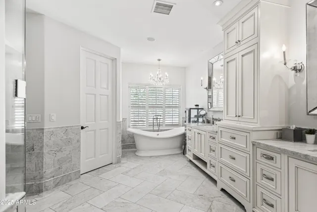 a bathroom with a granite countertop double vanity sink a mirror and a bathtub