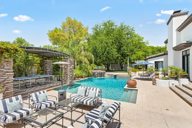 a view of a backyard with table and chairs potted plants and large tree