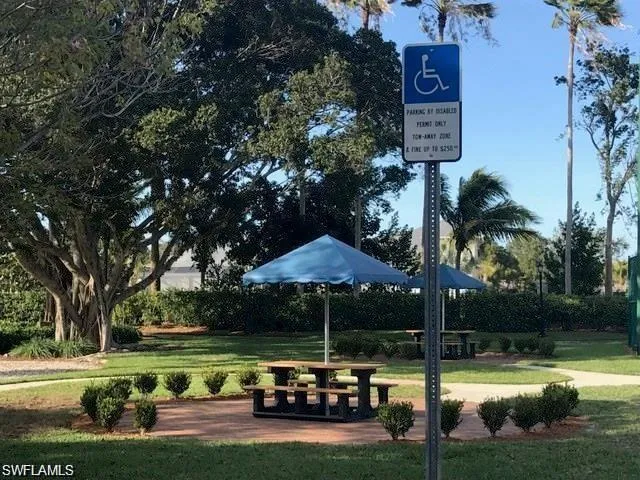 a view of swimming pool with lawn chairs and a table and chairs under an umbrella