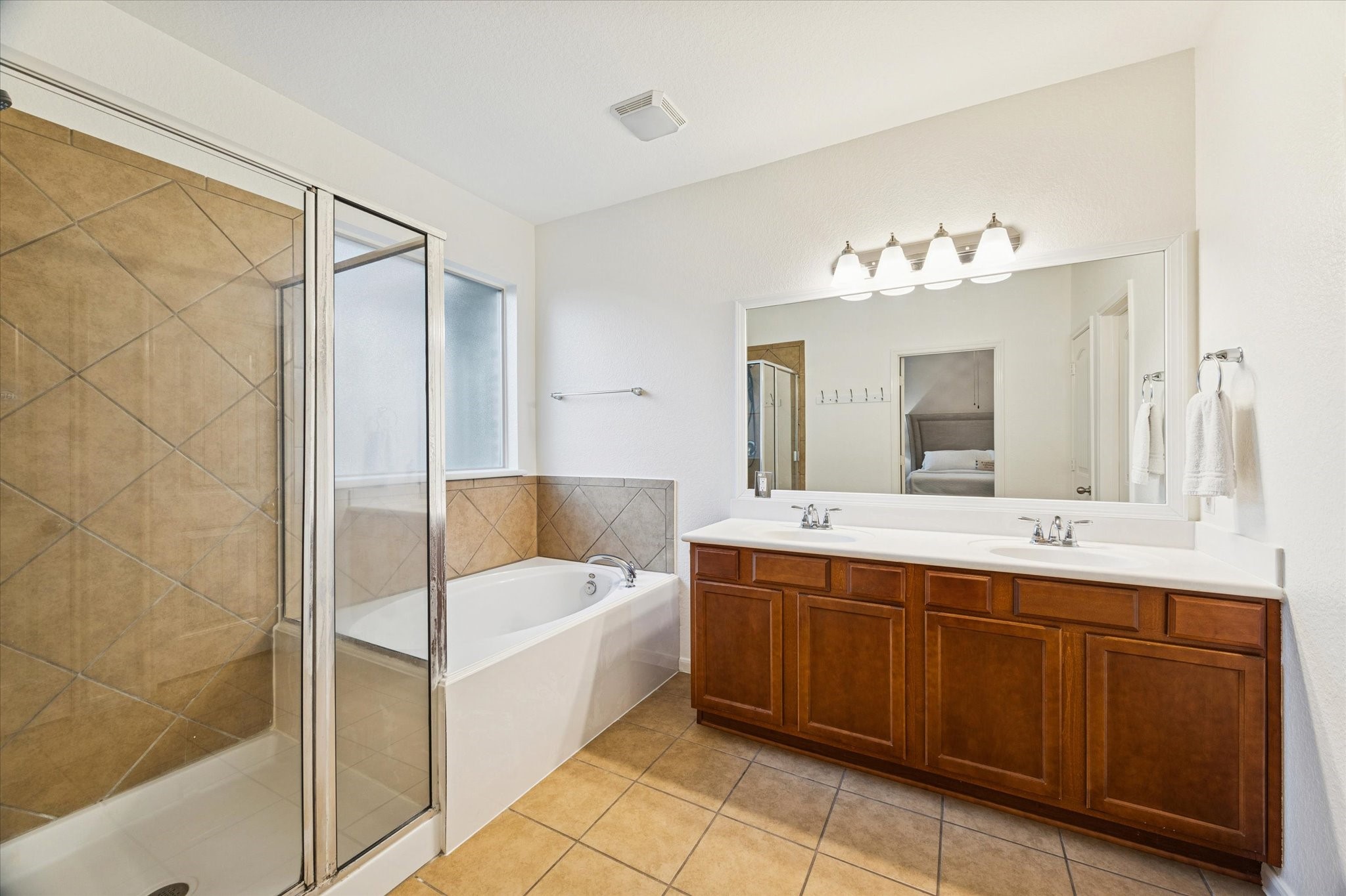 191 Maple Grove Drive Conroe, TX 77384 - Photo 13 of 27 Primary ensuite with dual sinks, large soaking tub and separate shower. Updated mirror and lighting (2025).