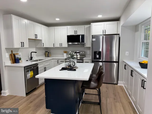 a kitchen with stainless steel appliances a refrigerator a sink a stove a table and chairs