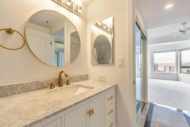 a bathroom with a granite countertop toilet sink and mirror