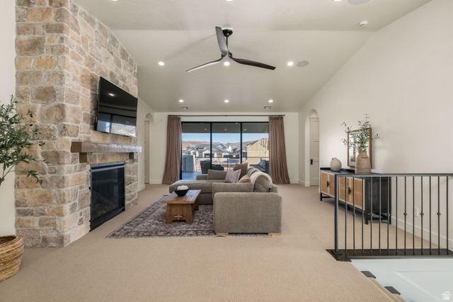 4871 South Homestead Way Washington, UT 84780 - Photo 68 of 151 Living room featuring arched walkways, light colored carpet, a ceiling fan, lofted ceiling, and a stone fireplace