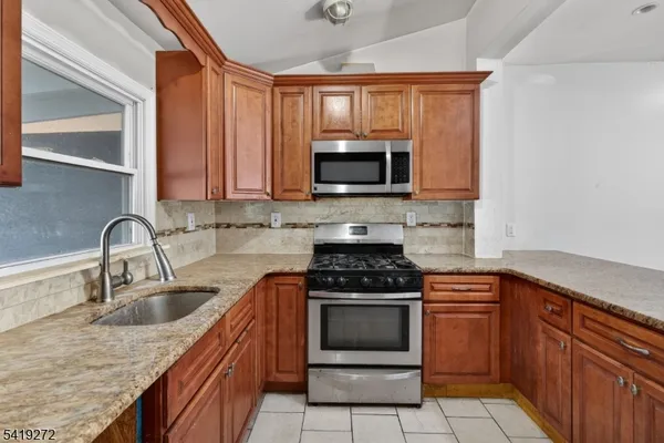 a kitchen with stainless steel appliances granite countertop a stove microwave and sink