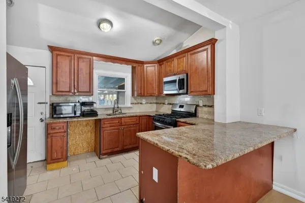 a kitchen with stainless steel appliances granite countertop a stove a sink dishwasher a refrigerator and a microwave oven