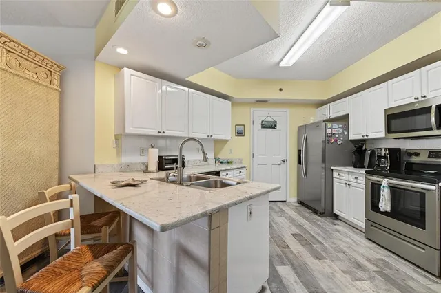 a kitchen with stainless steel appliances granite countertop a stove top oven a sink a dining table and chairs