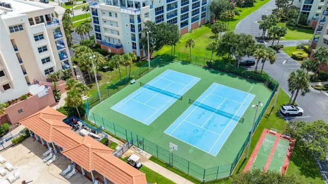 a multi story building with swimming pool and lawn chairs under an umbrella