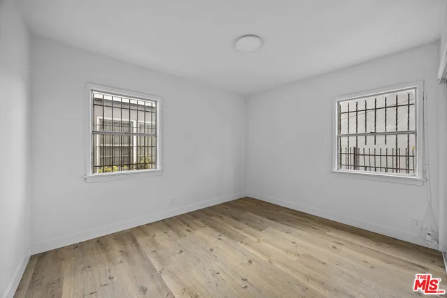 a view of an empty room with wooden floor and windows