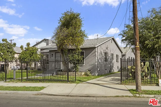 a view of a white house in a big yard with large tree