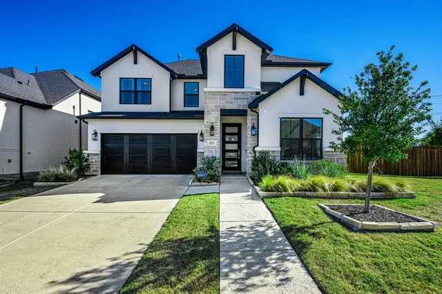 a front view of a house with a yard and potted plants
