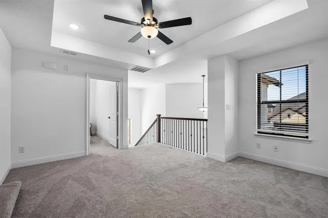 an empty room with ceiling fan and windows