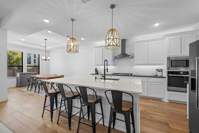 a kitchen with stainless steel appliances granite countertop a dining table chairs stove and white cabinets
