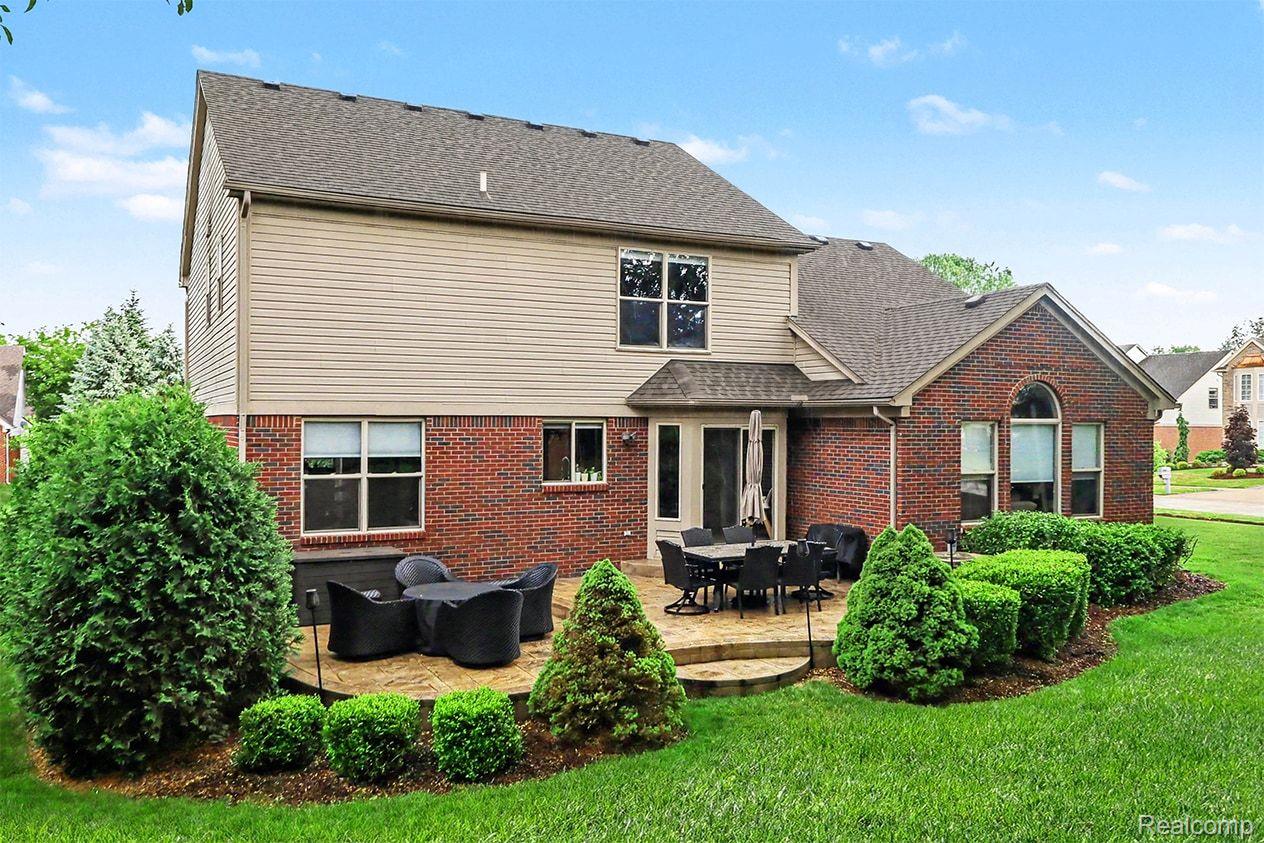 2548 Empire Court Rochester, MI 48309 - Photo 39 of 40 Tiered paver patio featuring a brick and siding exterior, arched window detail, and mature landscaping