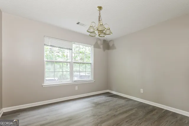 an empty room with wooden floor chandelier and window