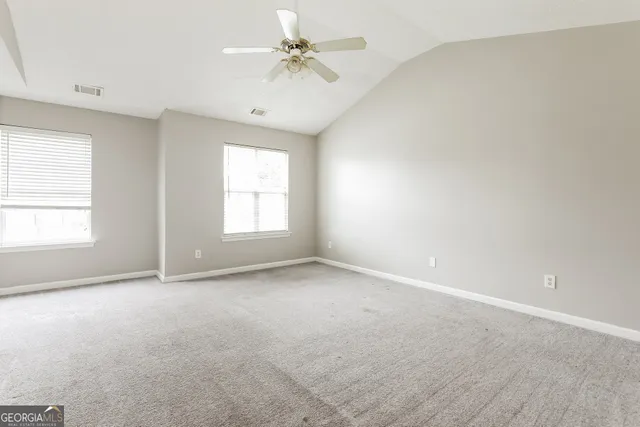 an empty room with windows and fan