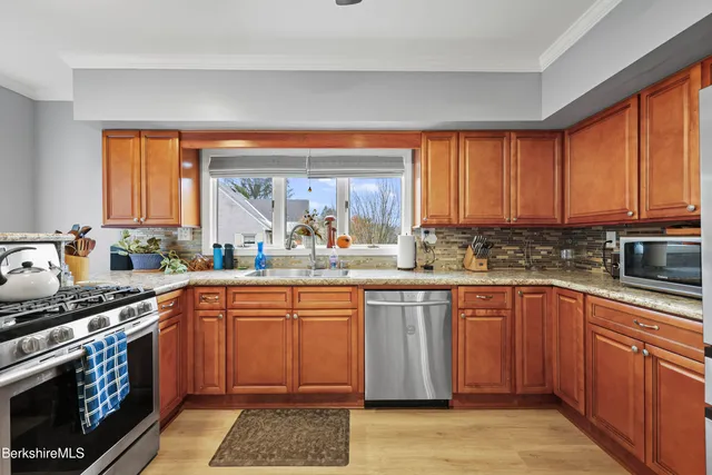a kitchen with stainless steel appliances granite countertop a stove a sink dishwasher and a microwave oven with large cabinets