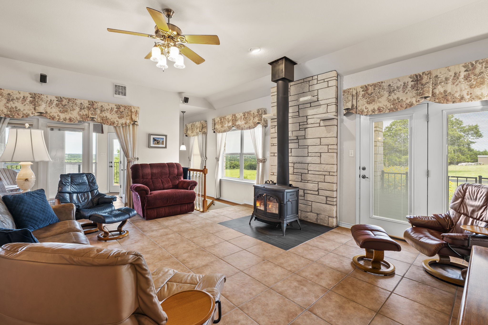 1427 River Ridge Ranch Road Killeen, TX 76549 - Photo 10 of 40 A spacious living area features a robust free-standing fireplace and multiple glass French doors opening to outdoor views.